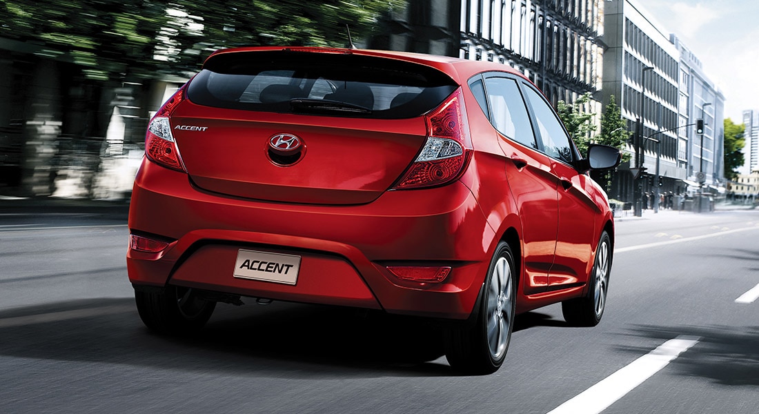 The exterior view behind the Hyundai Accent compact red hatchback car with five doors