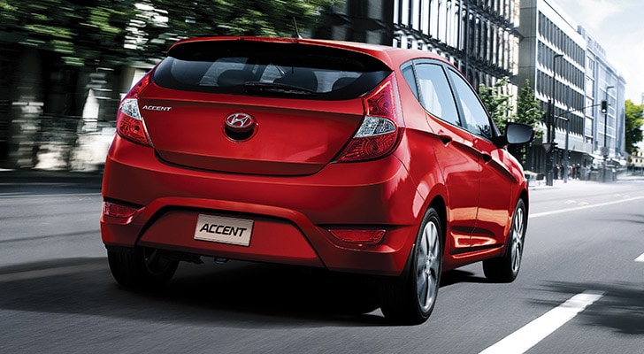 The exterior view behind the Hyundai Accent compact red hatchback car with five doors
