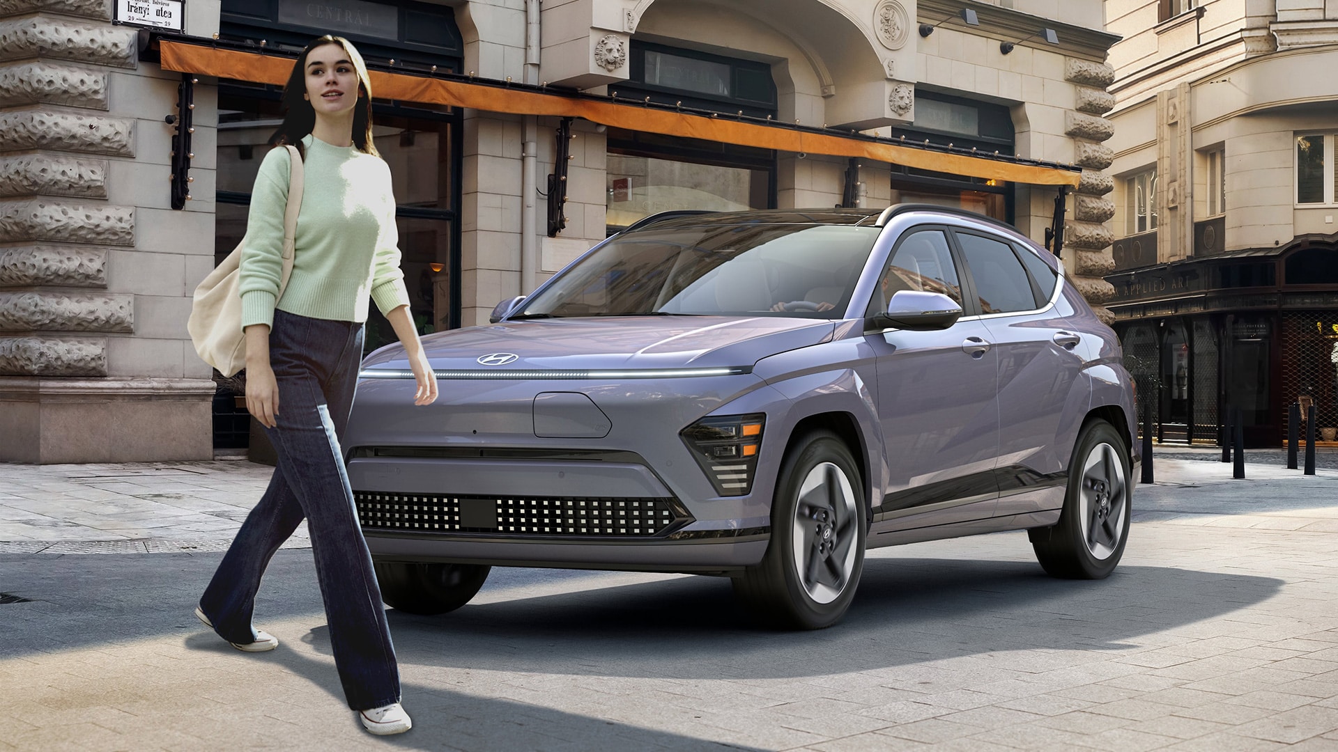 Image of a pedestrian walking in front of a 2024 grey KONA Electric 